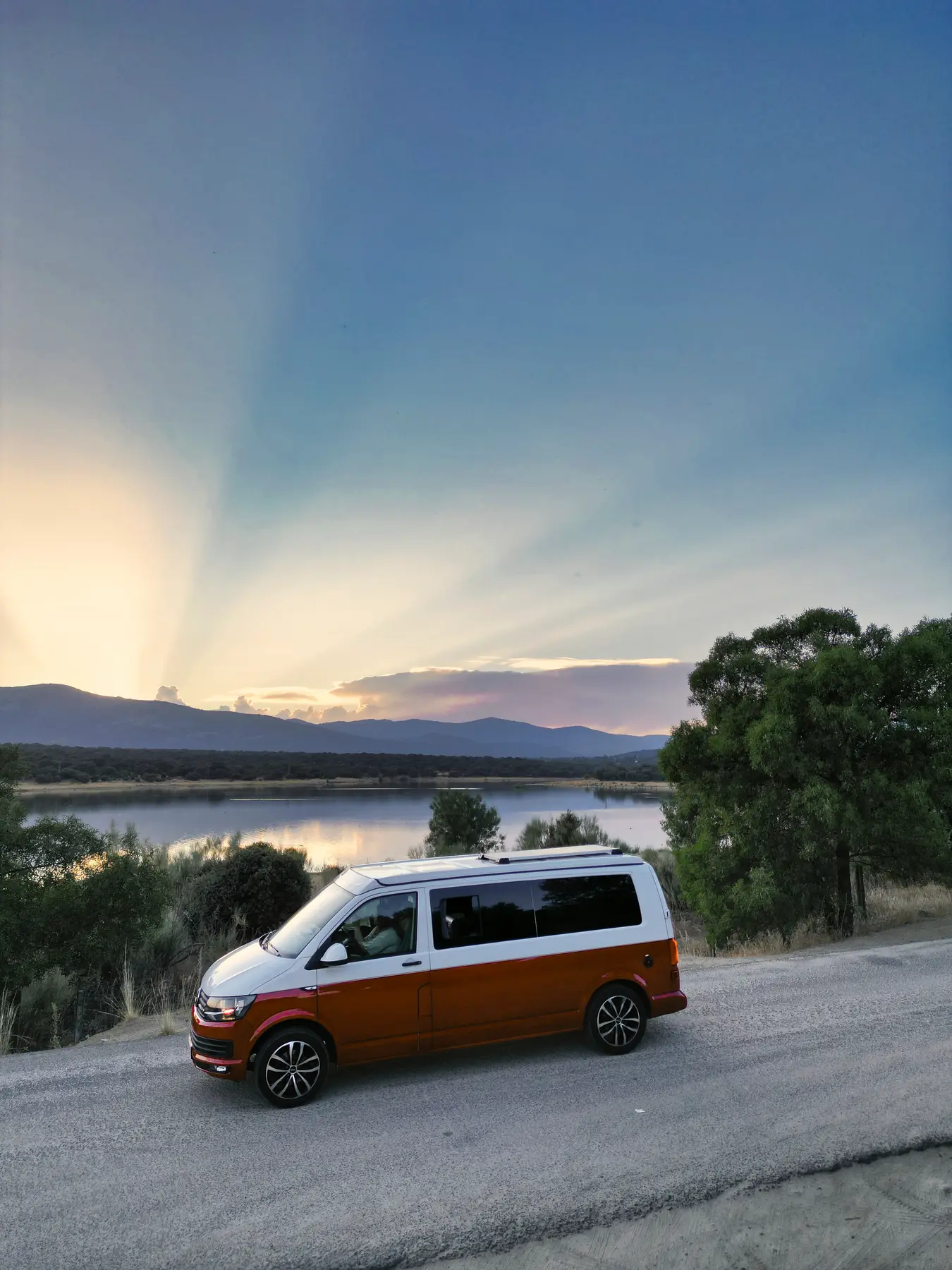 Camper beWinkle junto a un embalse con los rayos del sol al atardecer