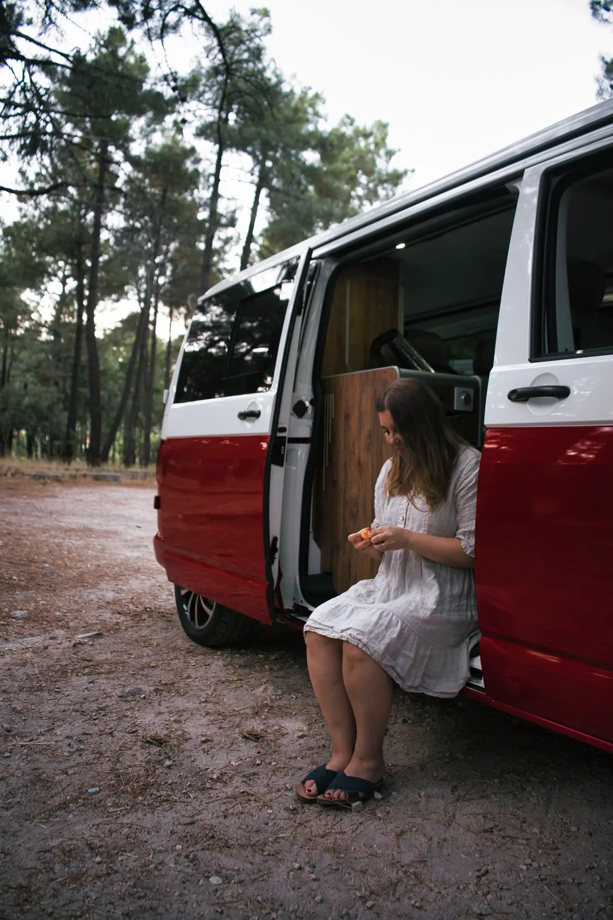 Viajera preparando sus cosas en la puerta de una camper beWinkle en un pinar